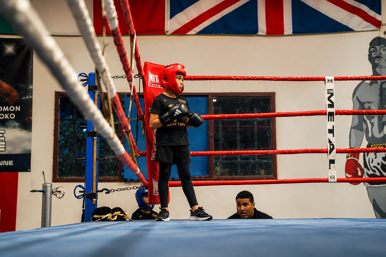 Jeune boxeur casqué dans le ring, un coach au bord du tapis